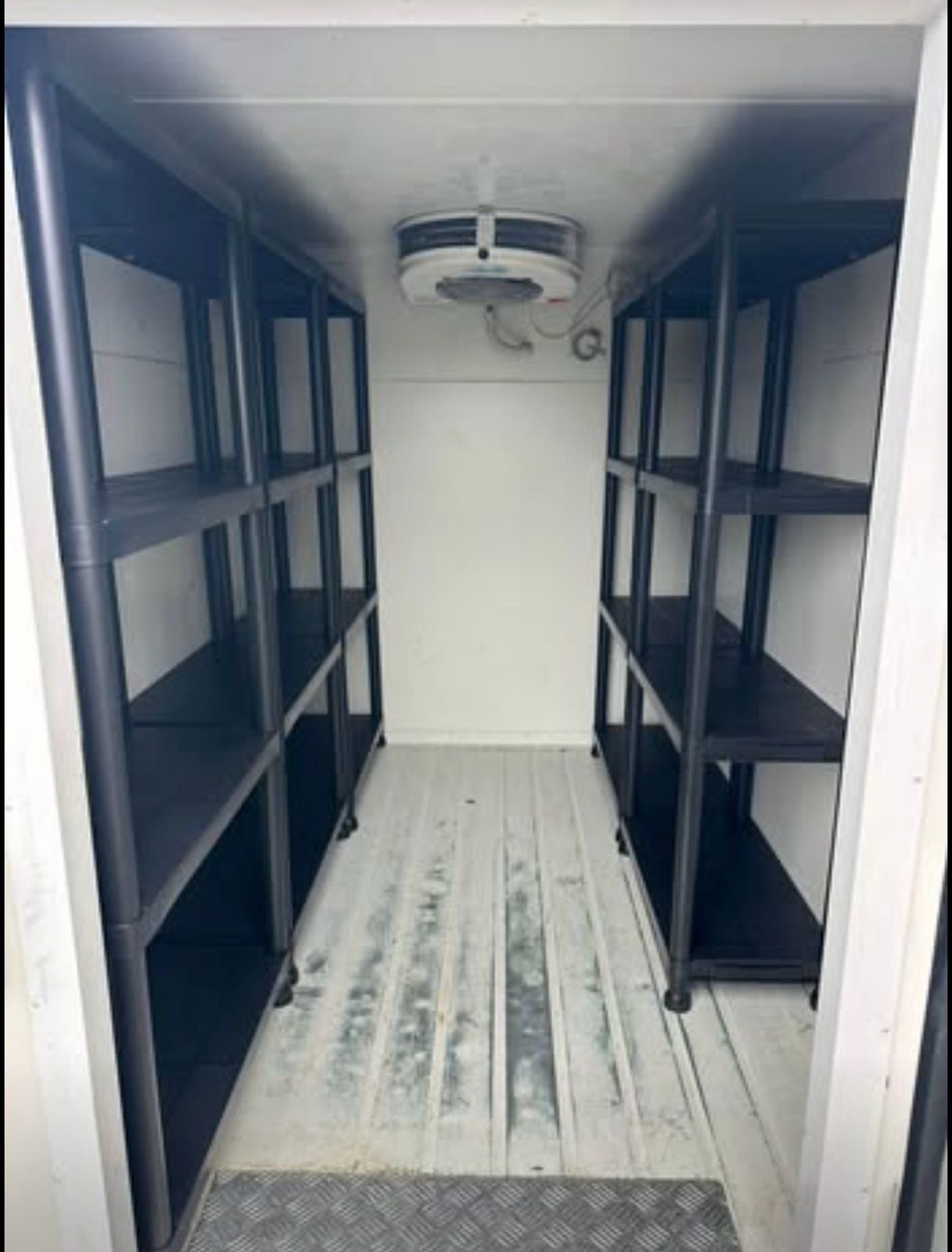 Interior of a chiller trailer with shelving and refrigeration unit